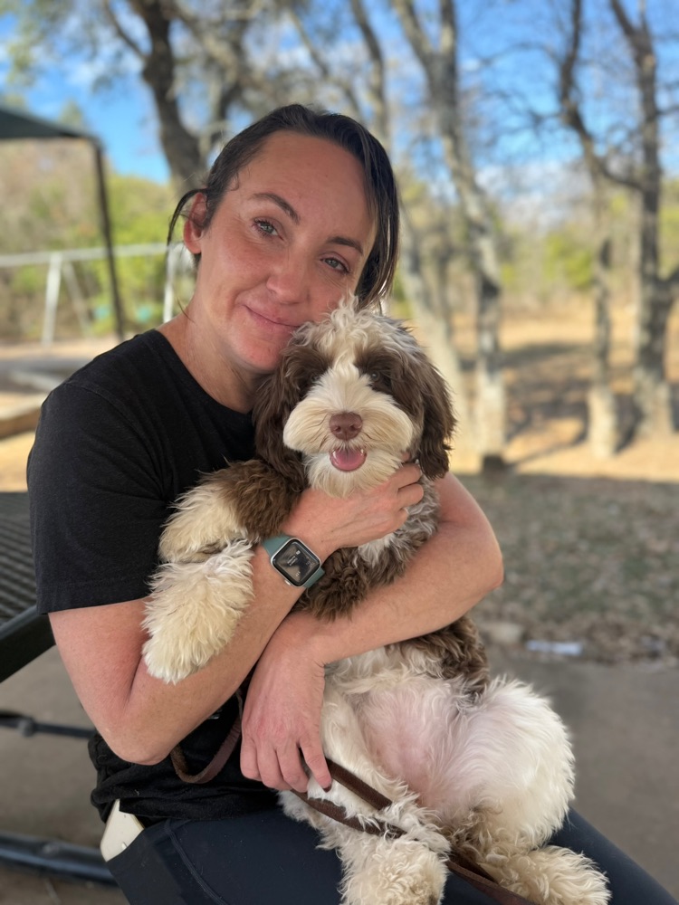 Cynthia Garlaska, owner of A Better Bond Dog Training, smiling with a dog